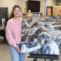 Gracie Rankin stands with her painting in the Tabor studio